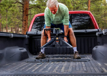 An older man easily lifting a CURT CrossWing 20K 5th Wheel Hitch into the back of his truck bed by himself