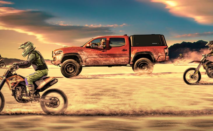 action shot of truck speeding through desert surrounded by motorcyclists with focus on RSI smartcap evo Adventure truck bed cover