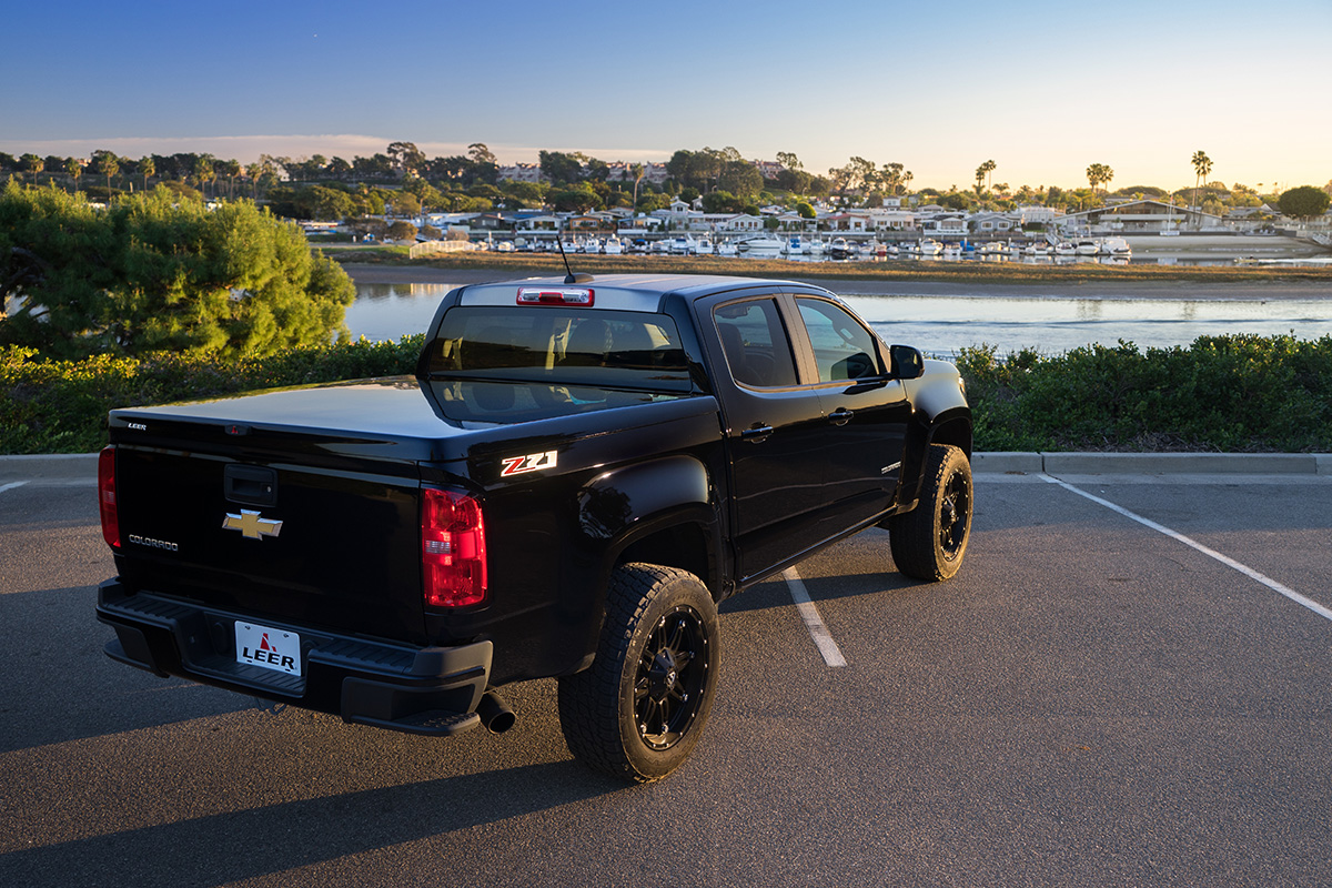 A black truck with a LEER 550 tonneau cover in a parking lot