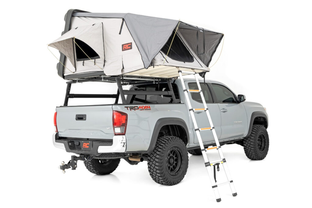 Rough Country Hard Shell rack-mounted tent mounted and opened on a grey Toyota off-road truck.