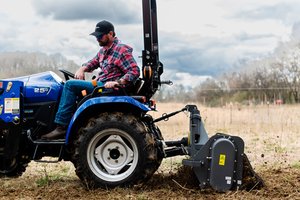 A farmer tilling a field with a Solectrac e25 electric tractor