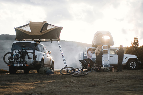 Two Thule Approach Rooftop Tents installed on top of off-road vehicles and set up at mountainous campsite
